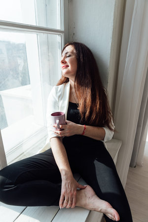 Beautiful brunette woman sitting by the window