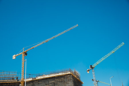 Crane and building construction site against blue skyの写真素材