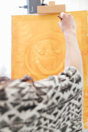 Woman painting yellow picture on canvasの写真素材