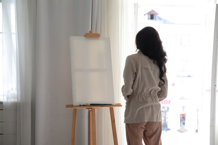 A woman artist at an easel in an art studio paints a pictureの写真素材