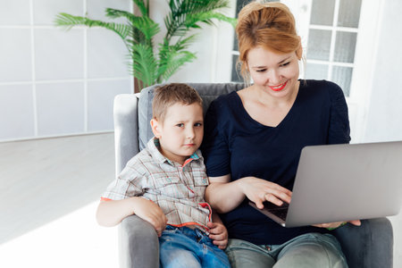 Woman with boy working on laptop onlineの写真素材