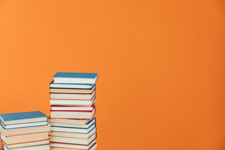 Stacks of educational books in library on orange backgroundの写真素材