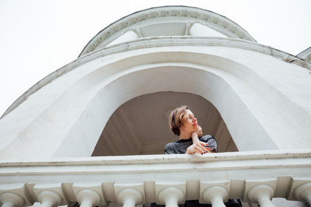 Beautiful woman in black clothes posing near a white buildingの写真素材