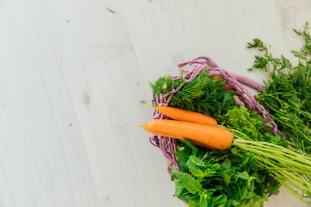 Fresh vegetables carrots and herbs in a bag on a gray table as backgroundの写真素材