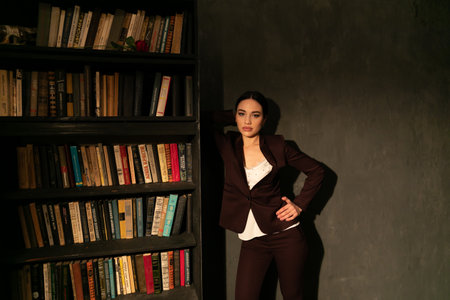 A business woman near a shelf with books in her officeの写真素材