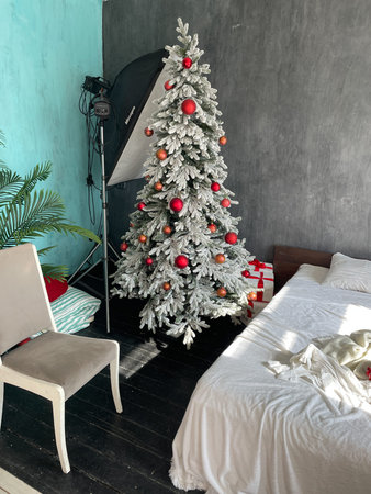 Christmas tree with gifts in the interior of a photo studio with a bedの写真素材
