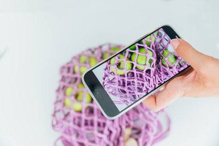 Smartphone in hand with a basket of apples on a white backgroundの写真素材