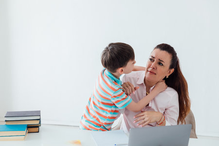 Boy distracts mom from working with laptopの写真素材