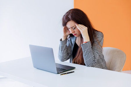 brunette woman closed her eyes tired at work with laptop onlineの写真素材