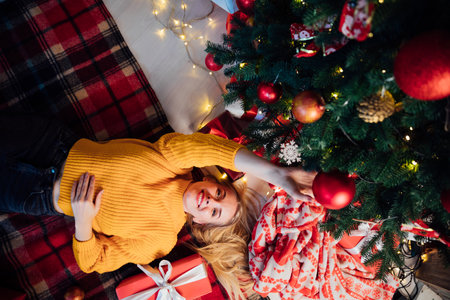 woman with gifts lying at christmas tree for new yearの写真素材
