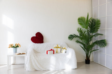 sofa with flowers and gifts for the holiday in the interior of the white roomの写真素材