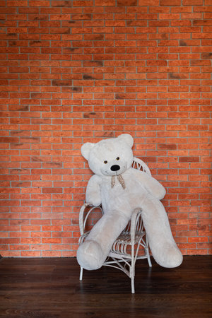 Toy Teddy Bear in an Armchair by a Brick Wallの写真素材