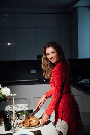 Woman housewife in red dress preparing a romantic dinner in the kitchenの写真素材