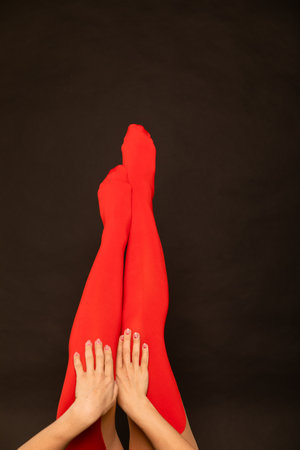 female legs in red tights stockings on a black backgroundの写真素材