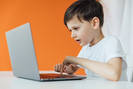 Schoolboy At Table Playing In Laptopの写真素材