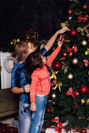 girl and mother decorate balloons at Christmas tree with gifts for the new yearの写真素材