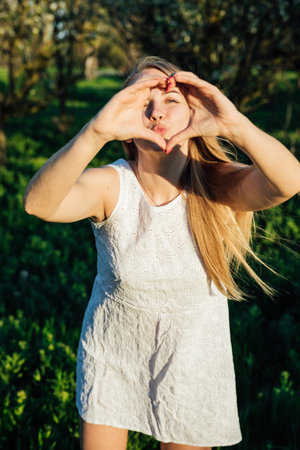 blonde woman showing her hands heart and kissの写真素材