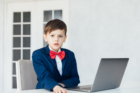 Little boy in business suit studying playing on laptop onlineの写真素材
