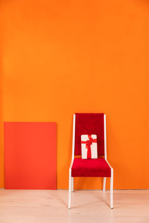 Festive gift on a chair in the interior of a yellow and orange living roomの写真素材