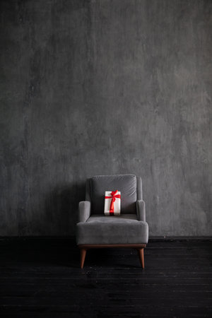 Armchair with gift in the interior of a dark gray roomの写真素材