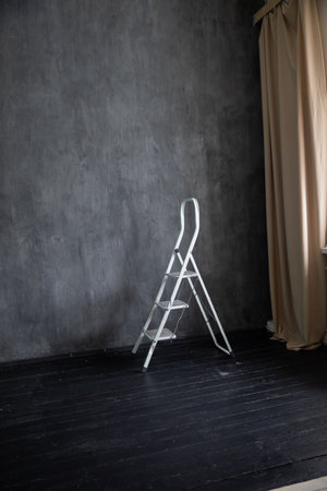 White stepladder for renovation in the interior of a dark gray roomの写真素材
