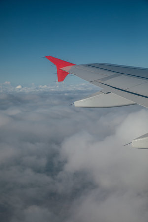 Airplane wings against sky background with clouds in flight