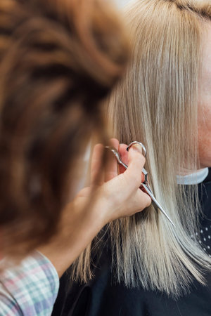 Hairstylist does a haircut styling for a woman in a hairdresser