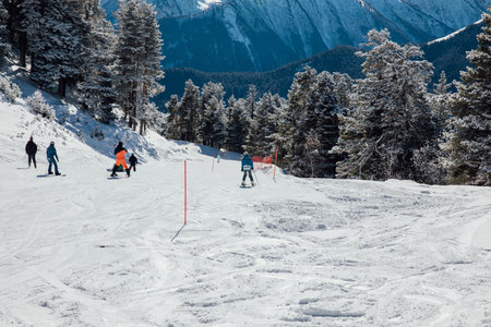 Skiers and snowboarders skiing on a snowy slope at a resortの写真素材