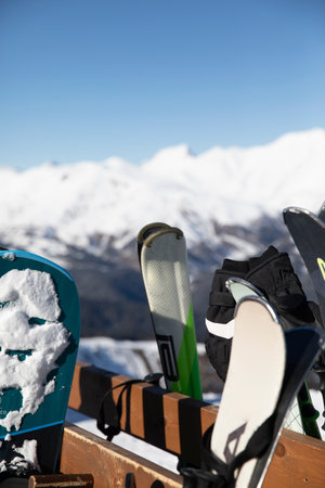 skis and snobboards stand on a shelf against the backdrop of the mountains of the ski resortの写真素材