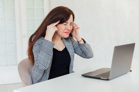 businesswoman has a headache from working with a laptopの写真素材