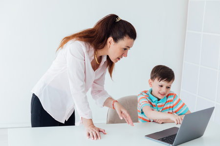 Female teacher helping boy on laptopの写真素材