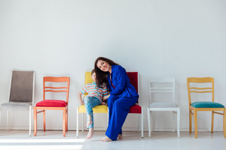Mother and son on different chairs in the interior of a white roomの写真素材