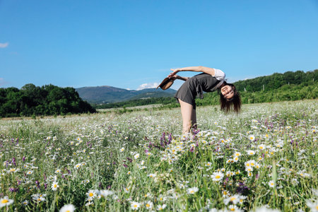 Beautiful woman in dress picking flowers in a field of daisies