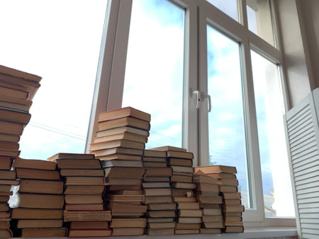 many stacks of books for learning at the window of the libraryの写真素材