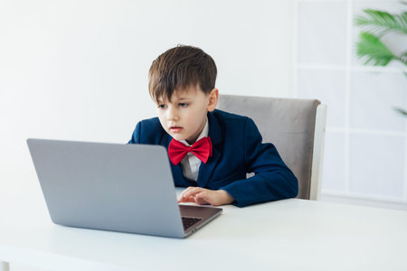 Boy in business suit at desk with laptop online