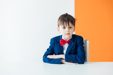 A school boy in a suit sits at a desk in a lessonの写真素材