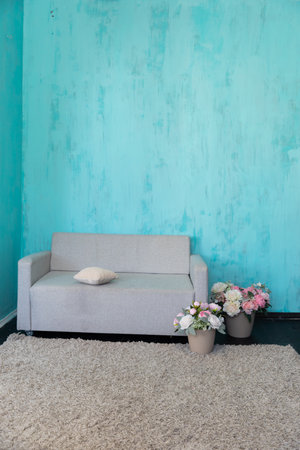 Gray office sofa with a vase of flowers in the interior of a blue roomの写真素材