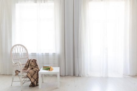 white old chair and table with book in the interior of a room with a windowの写真素材