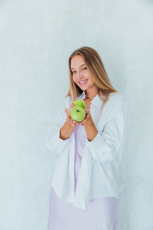 Beautiful blonde woman holding green fragrant apples for dietの写真素材