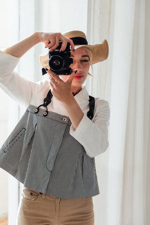 Female tourist in hat taking pictures with vintage camera