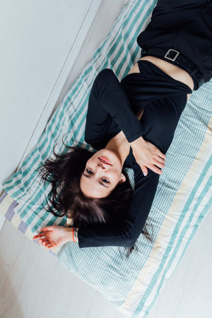 Slim woman in black clothes lying on mattressの写真素材