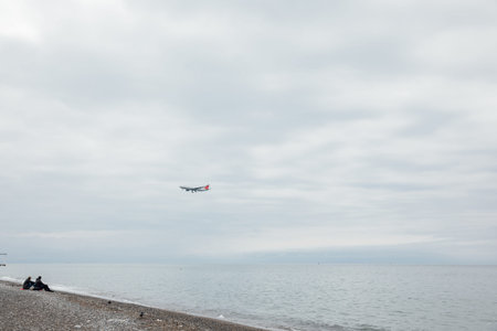 People on the beach watching a passenger plane