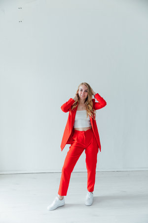 Business blonde woman in red suit smiling in bright officeの写真素材