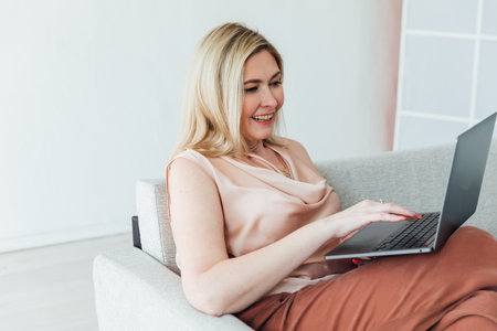 Business woman working on laptop negotiation online on sofa at homeの写真素材