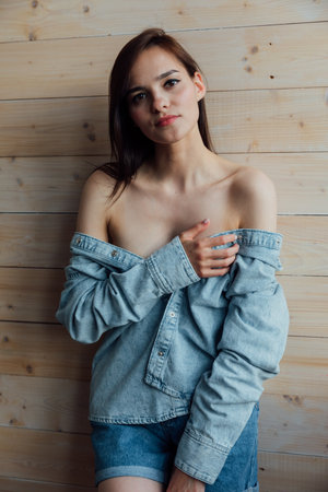 Brunette in off-the-shoulder denim on dark backgroundの写真素材