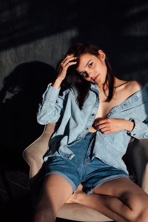 Brunette in off-the-shoulder denim on dark backgroundの写真素材