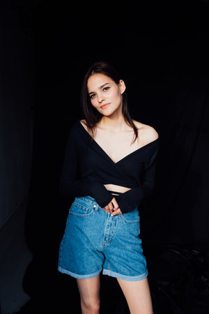 Brunette in off-the-shoulder denim on dark backgroundの写真素材