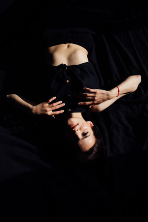 Slim brunette woman in black lingerie in bedroom on bed before bedの写真素材