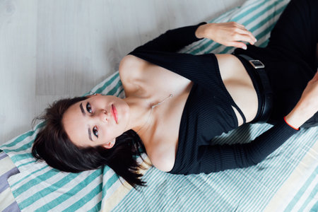 Slim woman in black clothes lying on mattressの写真素材