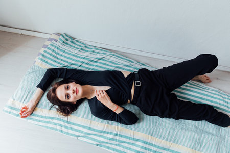 Slim woman in black clothes lying on mattressの写真素材